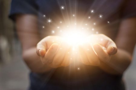 Stardust and magic in woman hands on dark background